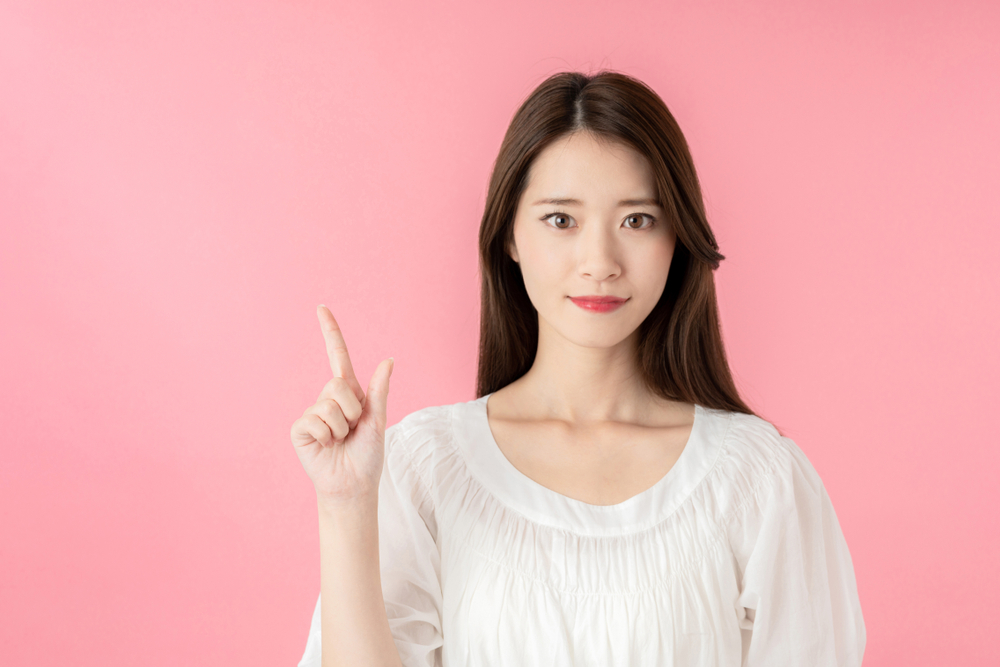 右手人差し指を立てている女性の画像